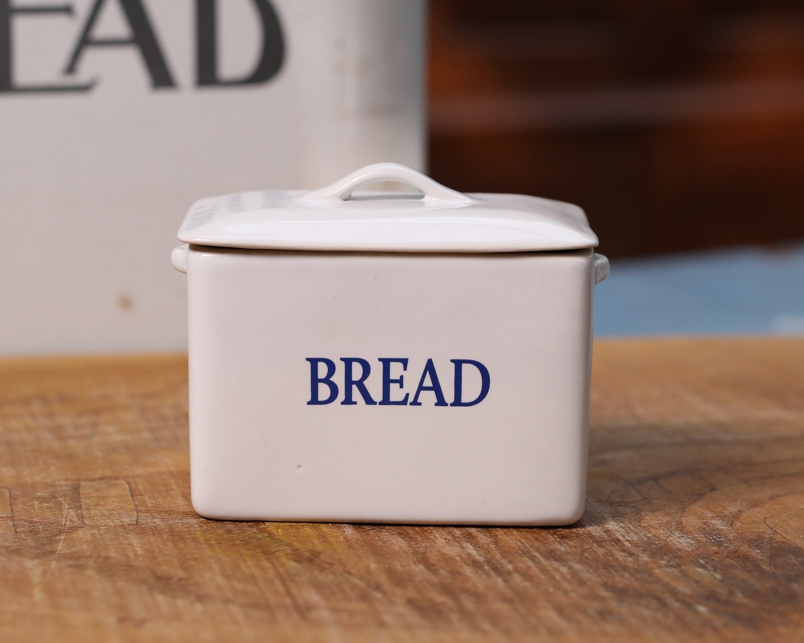Two vintage-style bread bins with 'BREAD' text on a wooden surface.